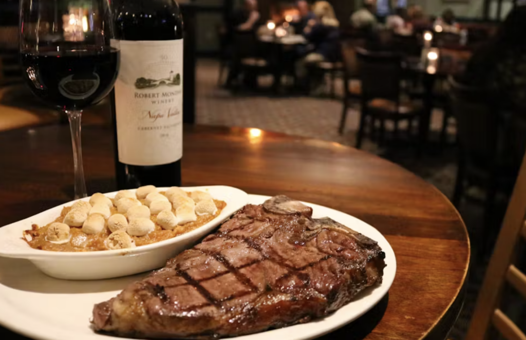 Steak with a glass of wine on a wooden tabletop in Memphis TN